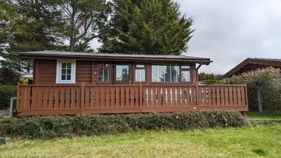 a wooden cabin with a fence in a yard at Snowdonia Log cabin in Trawsfynydd