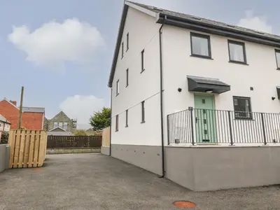 a white house with a green door on a driveway at 1 Crud Y Mor in Barmouth