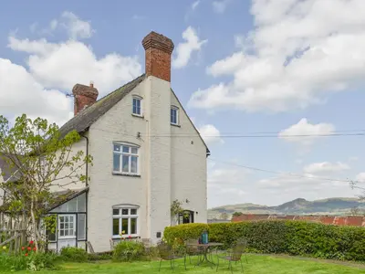 a white house with a chimney on top of it at Upper Broughton Farm Cottage in Snead