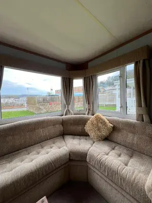 a large couch in a room with windows at Beautiful 2 bedroomed mobile home in Aberystwyth