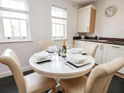 a white kitchen with a white table and chairs at 122 The Old Meadow in Shrewsbury