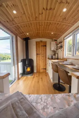 a room with a woodburning stove in a tiny house at Berllan Y Bugail Shepherds Hut in Llanwrda