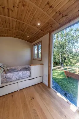 a bedroom with a bed and a large window at Berllan Y Bugail Shepherds Hut in Llanwrda
