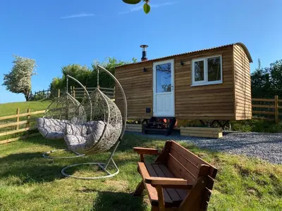 a tiny house with a bench in front of it at Berllan Y Bugail Shepherds Hut in Llanwrda
