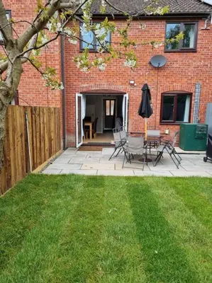 a patio with chairs and an umbrella in a yard at 41 mortimer drive, ideal location near ludlow in Orleton