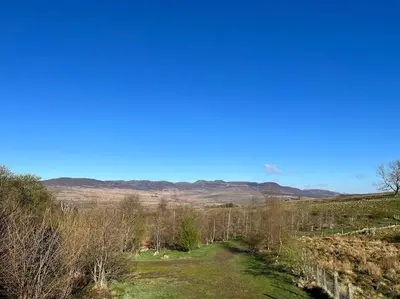 a path through a field with mountains in the background at Snowdonia Escape in Trawsfynydd