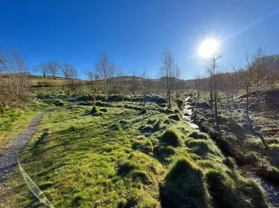 a grassy field with the sun in the sky at Snowdonia Escape in Trawsfynydd