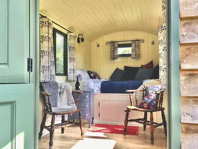a bedroom with a bed and two chairs in a room at Foxgloves and Fairytales Hut with Hot Tub in Llanwrda