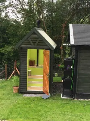 a small shed with a door in the grass at Foxgloves and Fairytales Hut with Hot Tub in Llanwrda