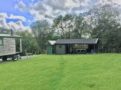 a small cabin in a field with a large yard at Foxgloves and Fairytales Hut with Hot Tub in Llanwrda