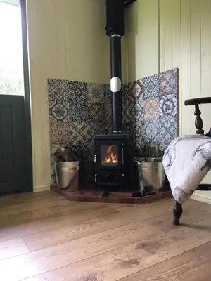 a wood burning stove in a room with a floor at Foxgloves and Fairytales Hut with Hot Tub in Llanwrda