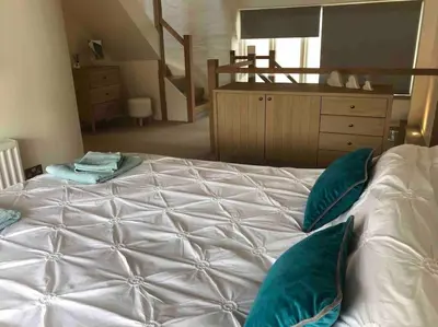a large white bed with green pillows in a bedroom at Ty Hobi Bach - at the foot of the Black Mountains in Brecon