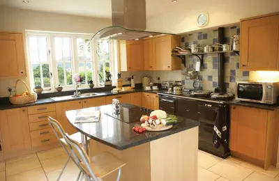 a kitchen with wooden cabinets and a island with a counter top at The Oaks in All Stretton