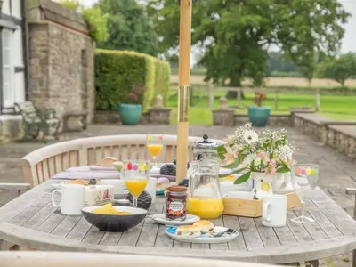 a wooden table with food and orange juice on it at Bearwood House & Cottage in Pembridge