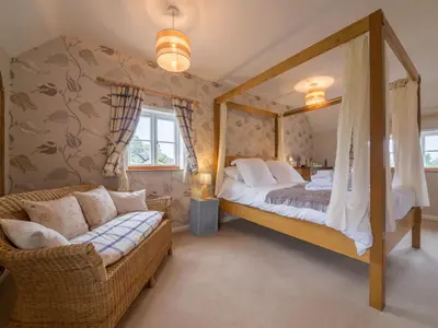 a bedroom with a four poster bed and a couch at Bearwood House & Cottage in Pembridge