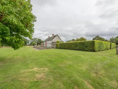 a large yard with a house and a hedge at Bearwood House in Pembridge