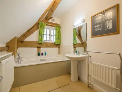 a bathroom with a bath tub and a sink and a bath tub at Bearwood Cottage in Pembridge