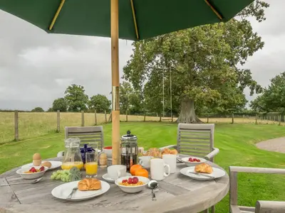 a picnic table with food on it with an umbrella at Bearwood Cottage in Pembridge