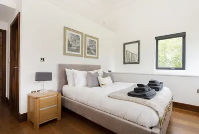 a white bedroom with a bed and a night stand at Wassell Barn in Craven Arms