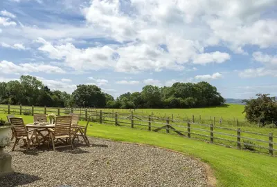 a table and chairs sitting next to a fence at Wassell Barn in Craven Arms