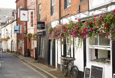 a narrow street with flowers hanging from buildings at Pear Tree Cottage Shropshire in Orleton