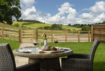 a wicker table with wine glasses and a plate of food at The Timber Barn in Downton
