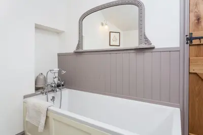 a bathroom with a mirror above a bath tub at Stone House in Leominster