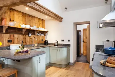 a kitchen with white cabinets and wooden walls at Stone House in Leominster