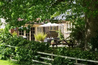 a house with a picnic table and an umbrella at Blacksmiths Cottage in Lingen