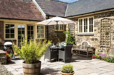 a patio with an umbrella and a table and chairs at Blacksmiths Cottage in Lingen