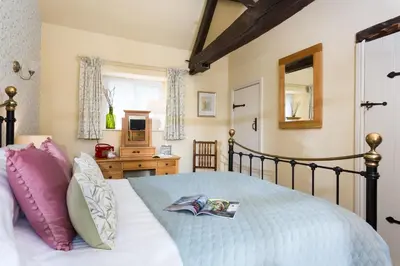 a bedroom with a bed with pink pillows and a mirror at Blacksmiths Cottage in Lingen