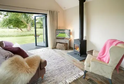 a living room with a couch and a wood stove at Broomers Barn in Lane to Richards Castle