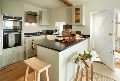 a kitchen with white cabinets and a black counter top at Unconformity Barn in Hope Bowdler