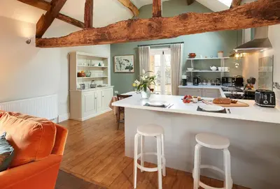 a kitchen and living room with a counter and stools at The Groom's Flat in Leominster