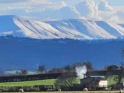 a house in a field with a snow covered mountain at Wye Valley Cabin in Upper Welson