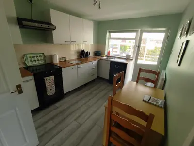 a kitchen with white cabinets and a table and a stove at Y Nyth in Newtown