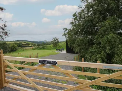 a wooden fence with a gate with a sign on it at Little Shelve Barn in Shrewsbury