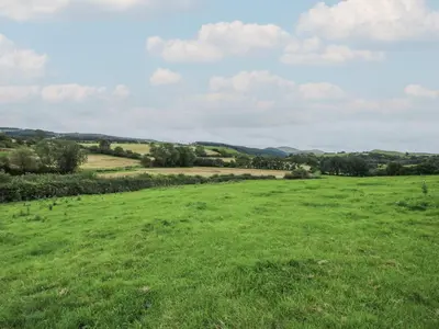 a field of green grass with hills in the background at Little Shelve Barn in Shrewsbury