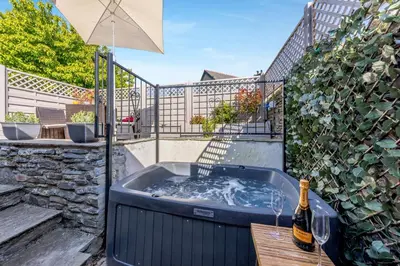 a hot tub on a patio with an umbrella at 1 Bed in Cerrigydrudion oc-bow194 in Cerrig-y-Druidion