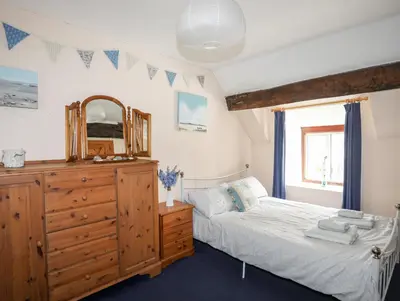 a bedroom with a bed and a dresser and a mirror at Gilfachwydd in Dolgellau