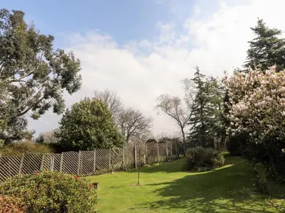 a fence in a yard with trees and flowers at Gilfachwydd in Dolgellau