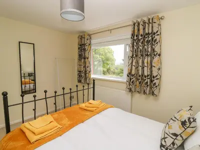 a bedroom with a bed and a window with curtains at Erwlon in Aberystwyth