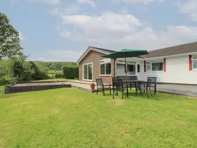 a patio with a table with a green umbrella at Erwlon in Aberystwyth