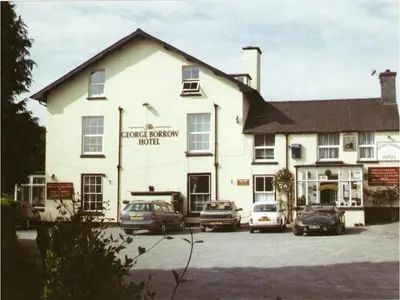 a large white building with cars parked in a parking lot at The George Borrow Hotel in Ponterwyd