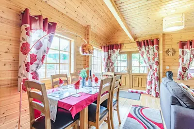 a dining room with a red table and chairs at Robin Lodge in Llanbedr