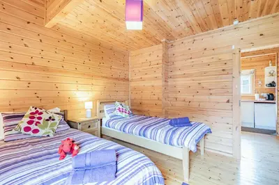 a bedroom with two beds in a log cabin at Robin Lodge in Llanbedr