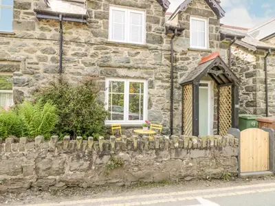 an old stone house with a stone fence at Y Bwthyn in Llanbedr