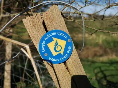 a sign on a wooden post with a logo on it at Y Bwthyn in Llanbedr