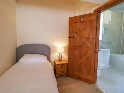 a bedroom with a bed and a wooden door at Bodnant in Tywyn