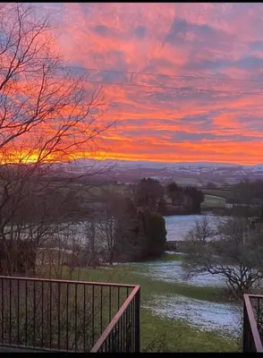 a sunset over a river with a fence at Pippin Lodge in Llanwrda